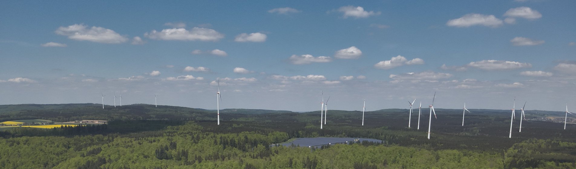 Drohnenbild des Solarparks Ochsenberg im Wald, umgeben von Windrädern.