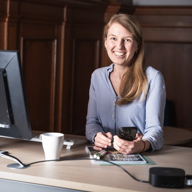 Lächelnde Mitarbeiterin an einem Büroarbeitsplatz.